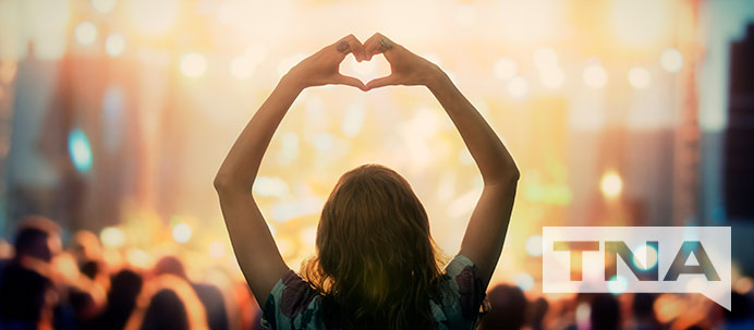 Woman making a love heart with her hands at a music festival stage